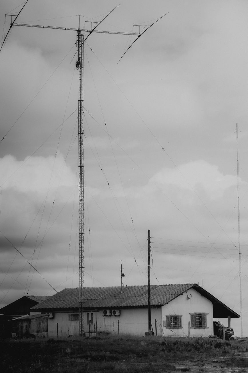 tall radio tower beside rural house in grayscale